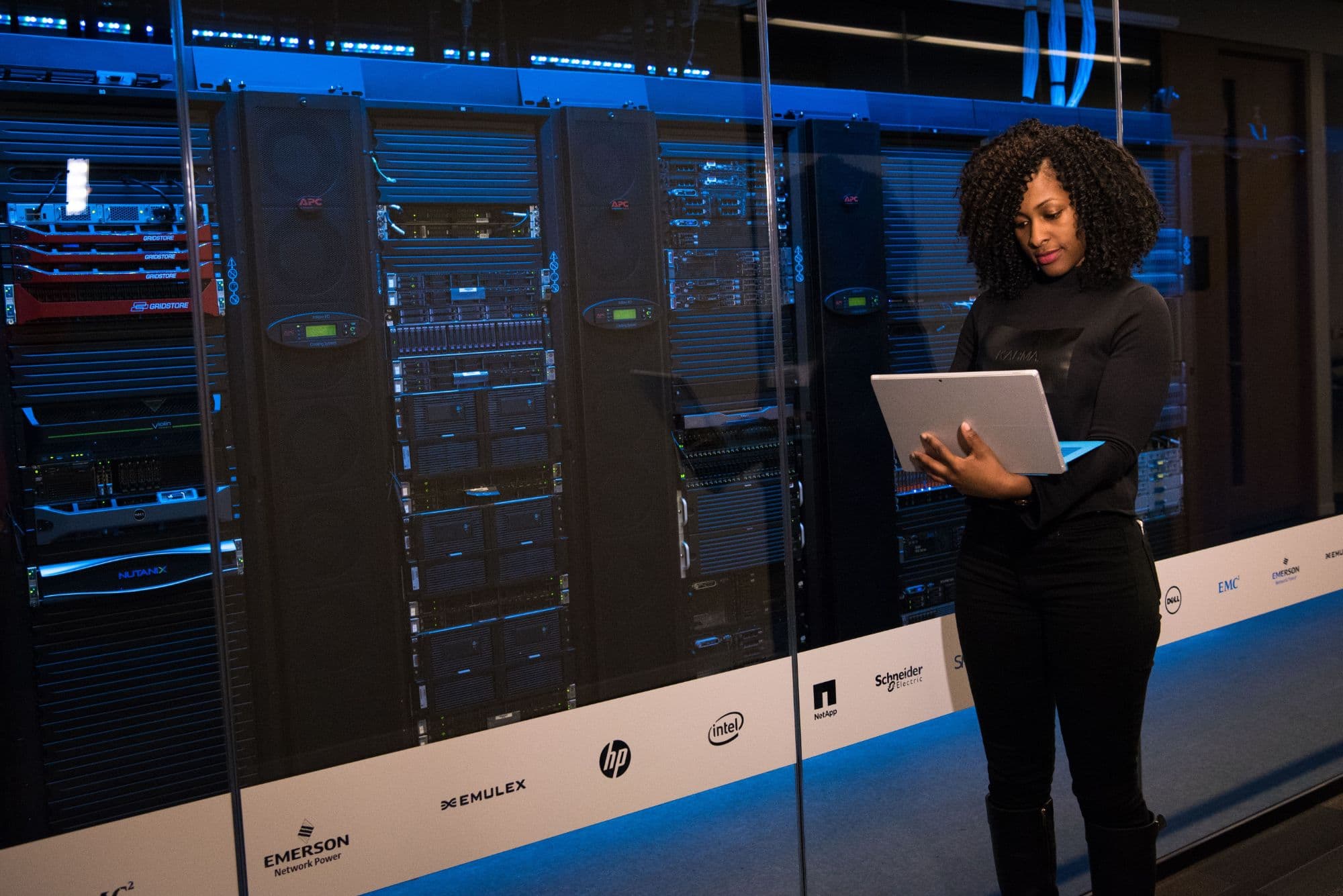 A data center technician with a laptop in front of a long row of server racks